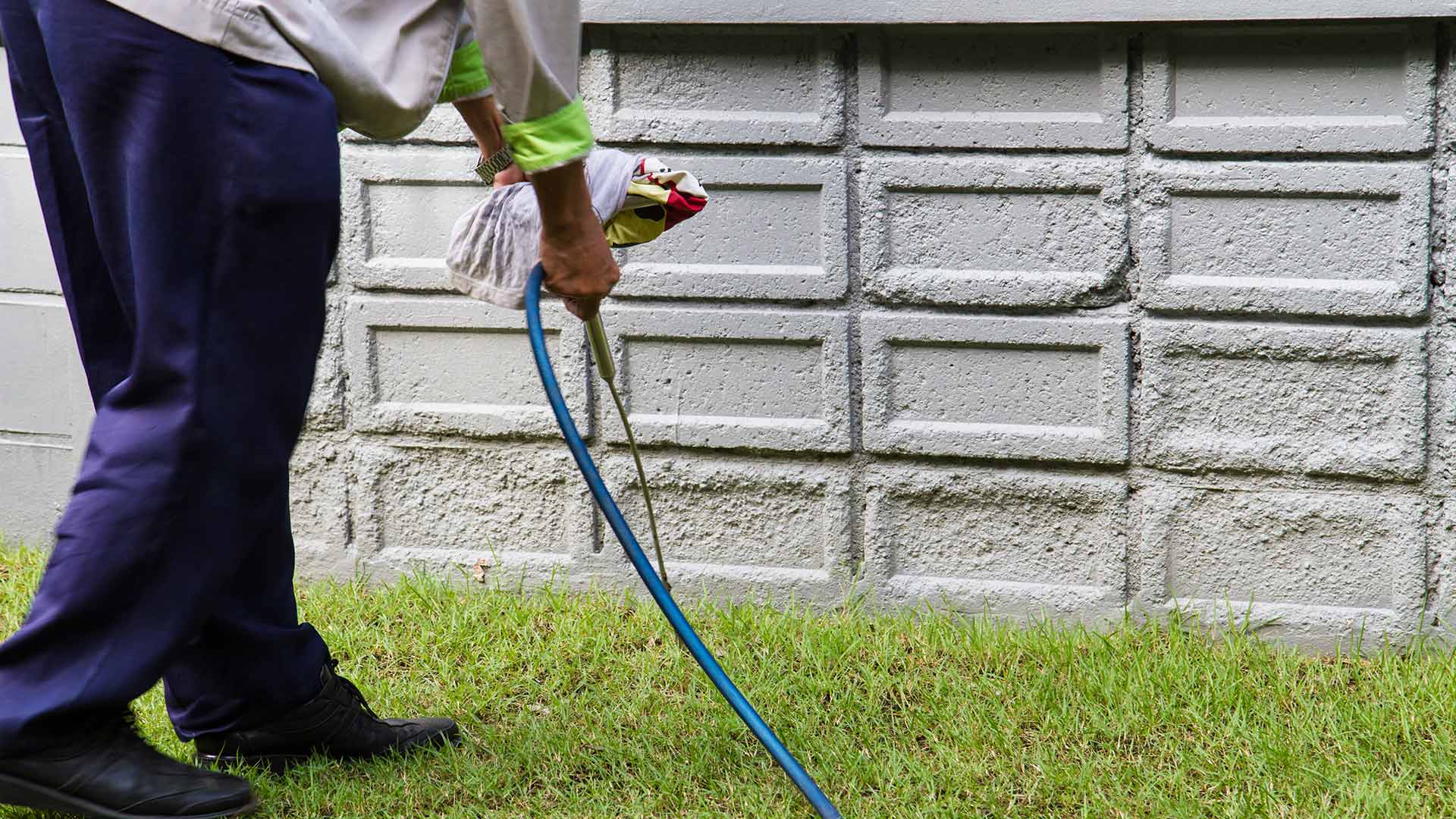 A professional spraying the perimeter of a home with a pest control solution.