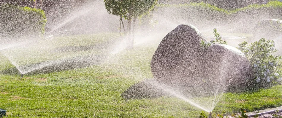 Irrigation sprinklers watering shrubs and grass in The Villages, FL.