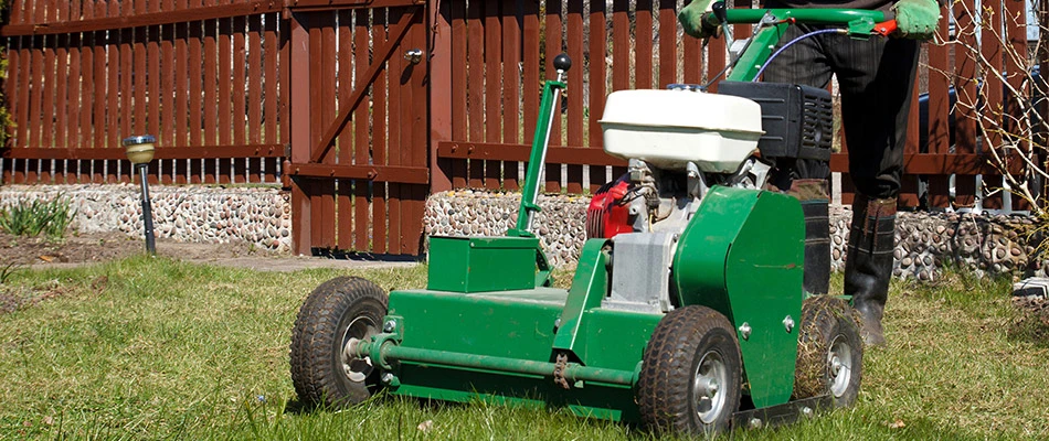 A professional pushing an aerator machine over a lawn in Lady Lake, FL.