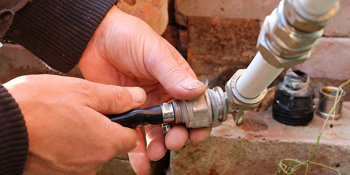 An irrigation system's pipes and monitoring system is being repaired by an lawn care expert.