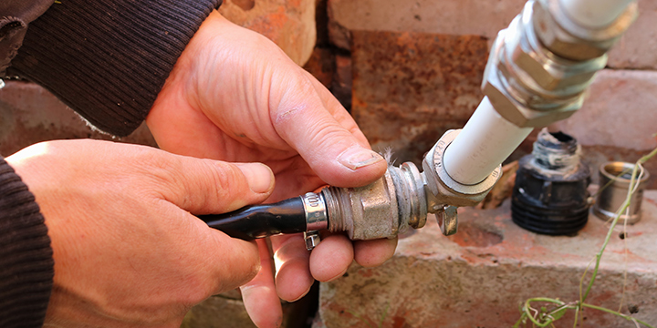 An irrigation system's pipes and monitoring system is being repaired by an lawn care expert.