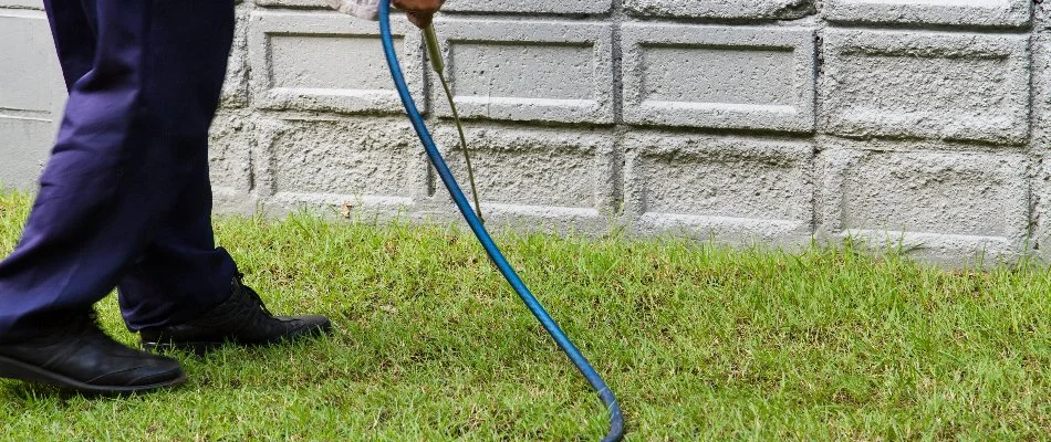 Perimeter pest control treatment being applied to the side of a house in The Villages, FL.